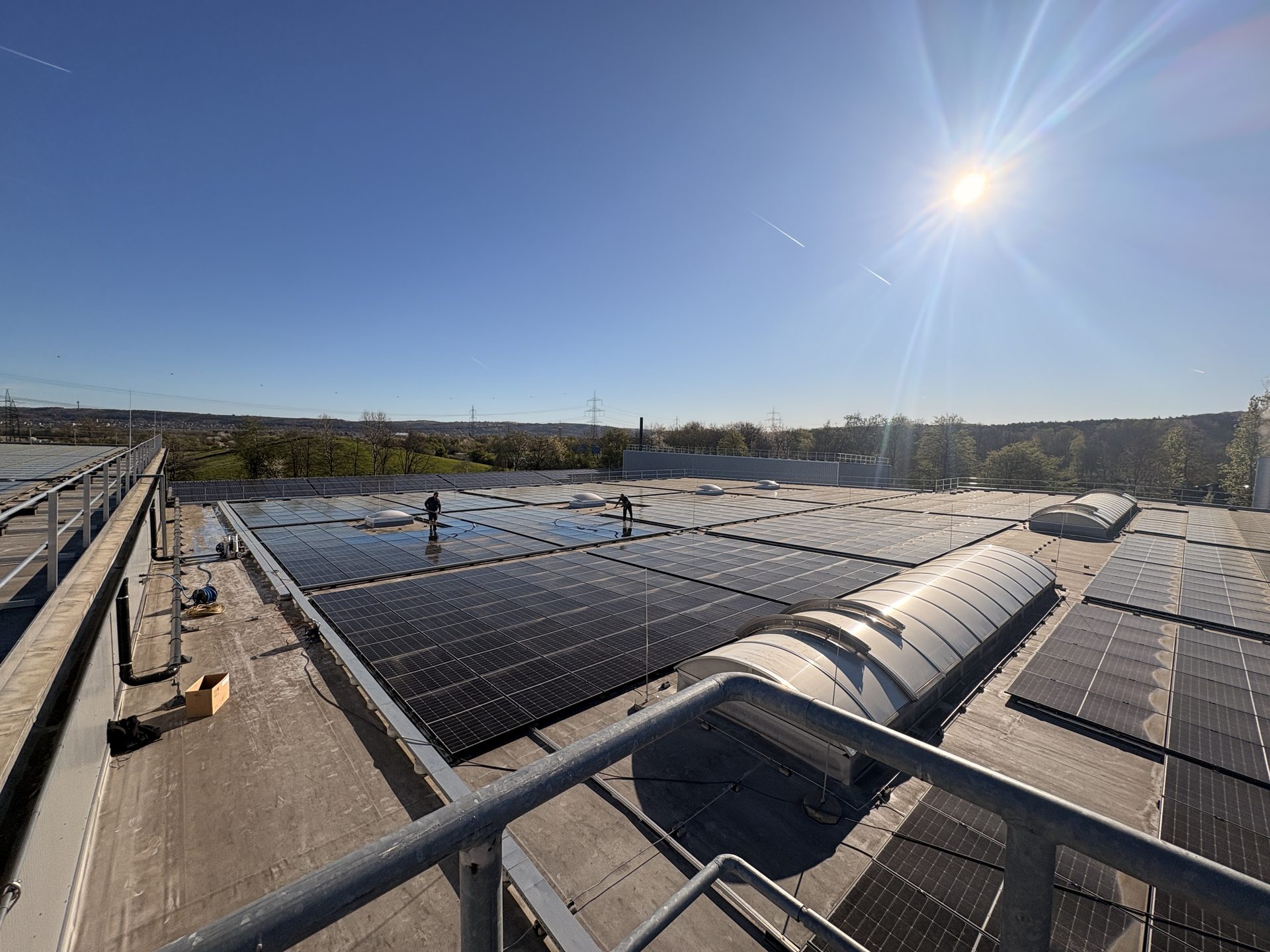 EMS reinigt eine große Photovoltaik-Anlage auf einem Gewerbedach in der Sonne