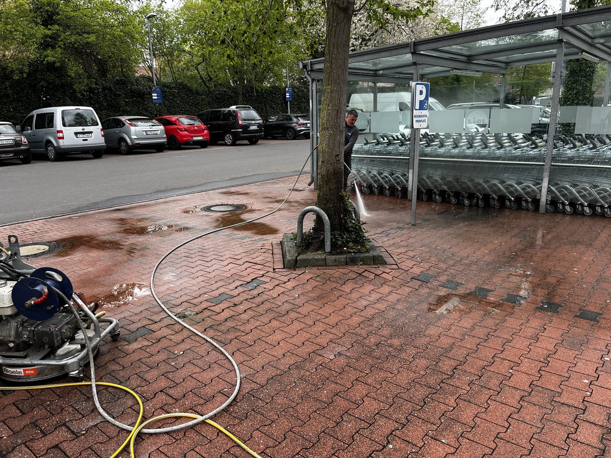 EMS reinigt eine Einkaufswagen-Station auf einem Supermarktparkplatz