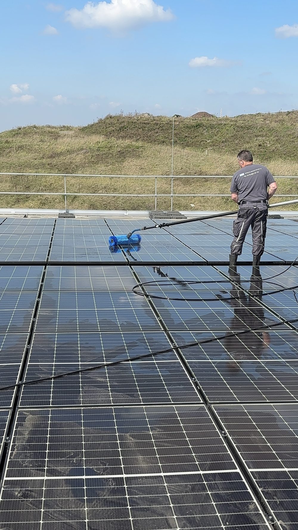 EMS-Mitarbeiter reinigt eine Photovoltaik-Freiflächenanlage mit Teleskopbürste