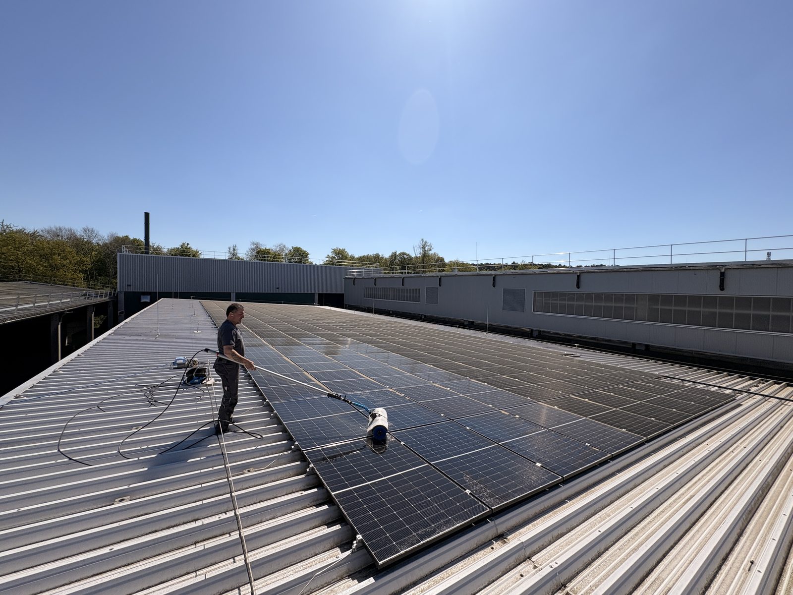 EMS-Mitarbeiter reinigt Photovoltaik-Module auf einem Gewerbedach